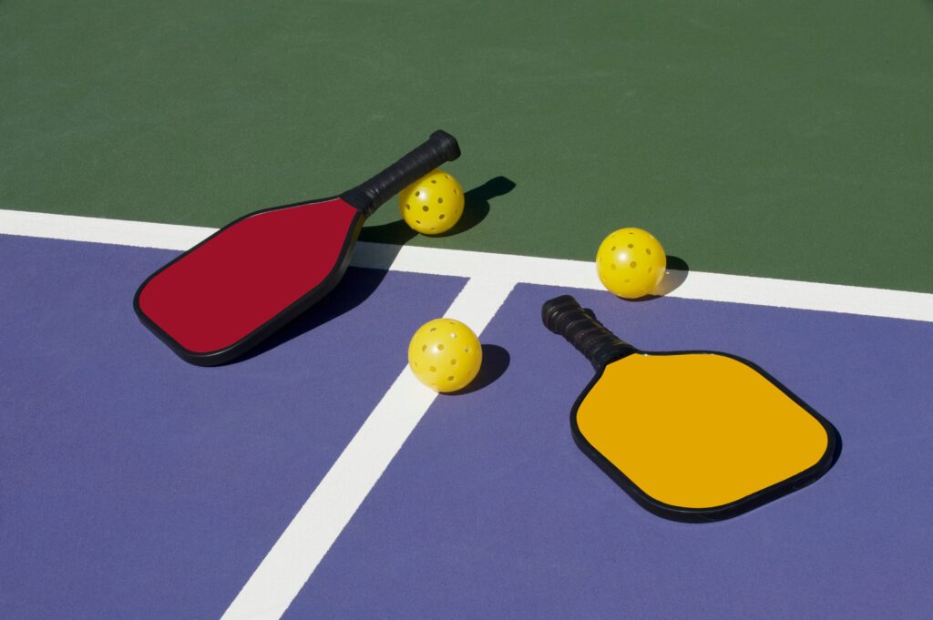 pickleballs and paddles on a pickleball court